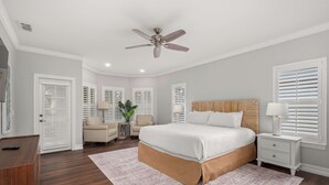 A bedroom with a large bed, a ceiling fan, white walls, and a wooden floor. - Reunion villa w/ pool & cinema room (Kissimmee)