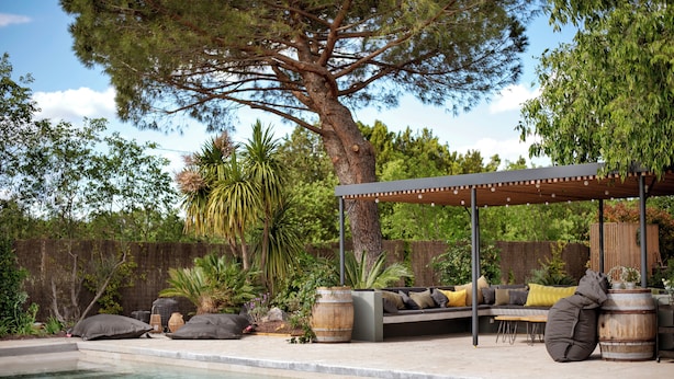 Zona de piscina con un porche de madera, asientos con cojines y un gran árbol.