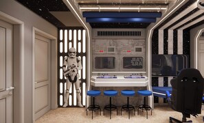 Ett rum med Star Wars-tema, inklusive en Stormtrooper-figur, en kontrollpanel och en bardisk med barstolar.