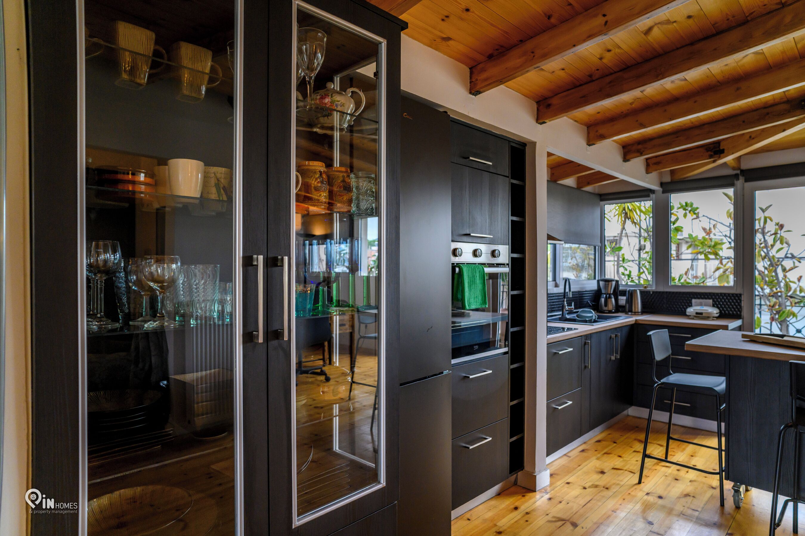 Une cuisine moderne avec des meubles de couleur sombre, un four encastré et un coin bar avec des tabourets.