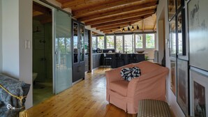 Ein großzügiger Wohnbereich mit Holzbalkendecke, einem rosa Sofa und einer Küche im Hintergrund.