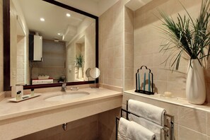 Une salle de bain avec deux lavabos, un grand miroir, un porte-serviettes et une plante en pot.