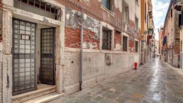 Una calle estrecha con edificios antiguos, un hidrante visible y un cielo despejado.