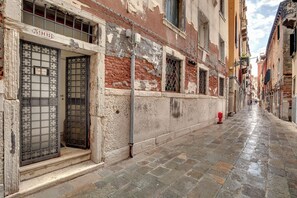 Une rue étroite bordée d’immeubles anciens, avec une borne d’incendie bien visible et un ciel dégagé.