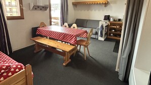 A cozy room with two wooden beds, a sofa, a small table, and a kitchenette area. - Bright studio in Risoul, ski on foot and comfort (Risoul)