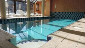 An indoor swimming pool with clear water, tiled walls, and sunlit areas with lounge chairs. - Bright studio in Risoul, ski on foot and comfort (Risoul)