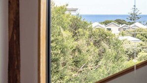 Une chambre avec une fenêtre donnant sur un quartier résidentiel et la mer.