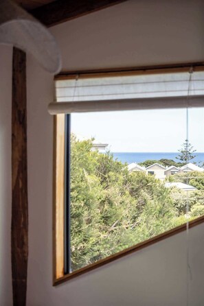 Ein Zimmer mit Fensterblick auf eine Wohngegend und das Meer.