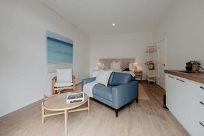 A modern living room with a sofa, a round coffee table, and a painting of a beach. - Bailey Estate—Margaret River Lakeside Stay (Rosa Brook)