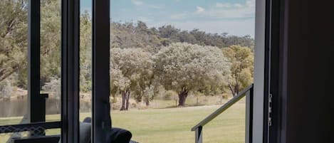 A room with a sliding glass door leading to an outdoor area with a view of trees and a grassy field.