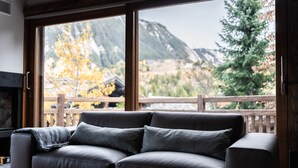 A modern living room with a leather sofa, large windows offering a view of a mountainous landscape. - Chalet Orrana in the heart of Courchevel Village (Courchevel)