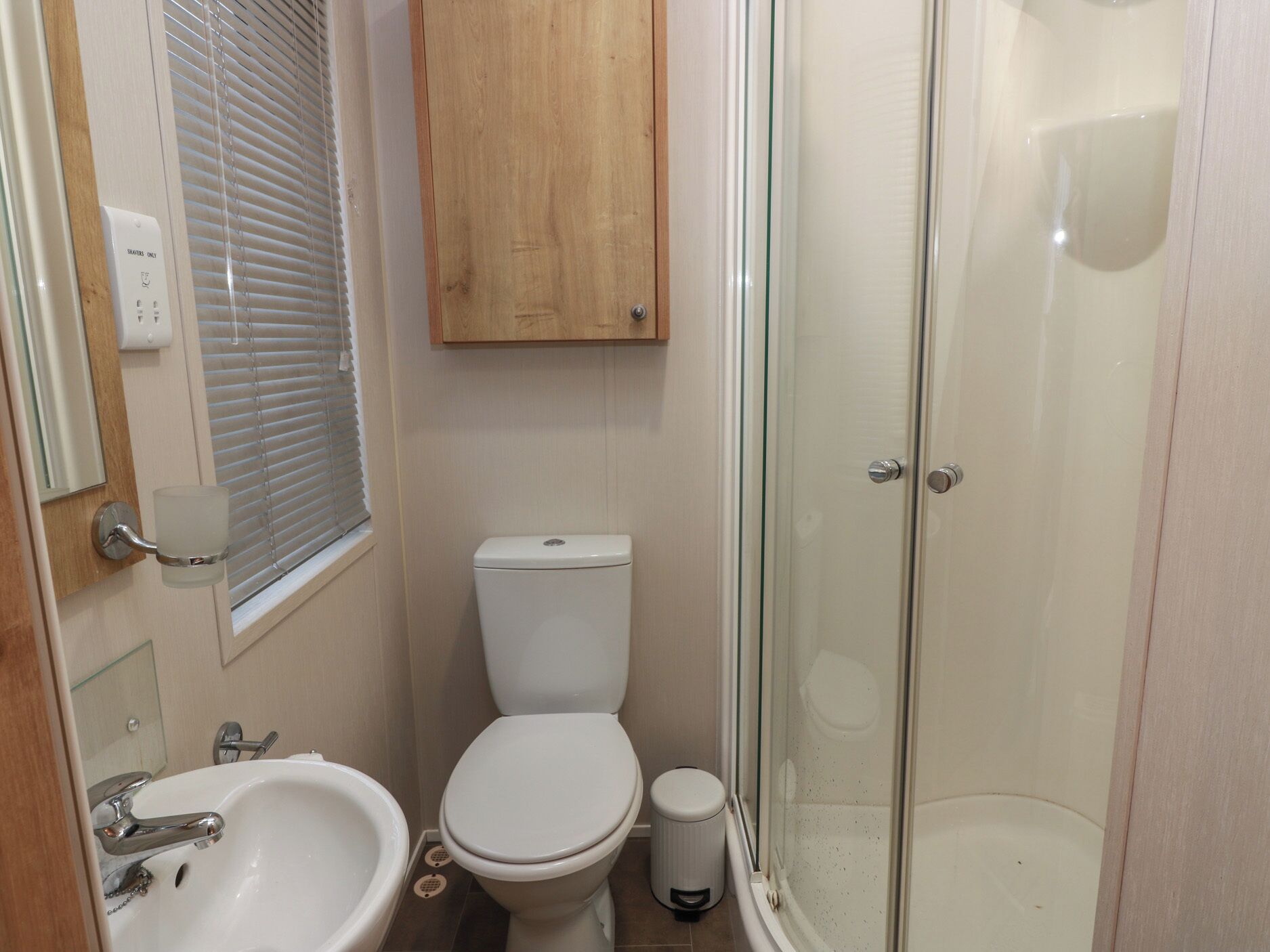 A bathroom with a toilet, sink, and glass shower enclosure.