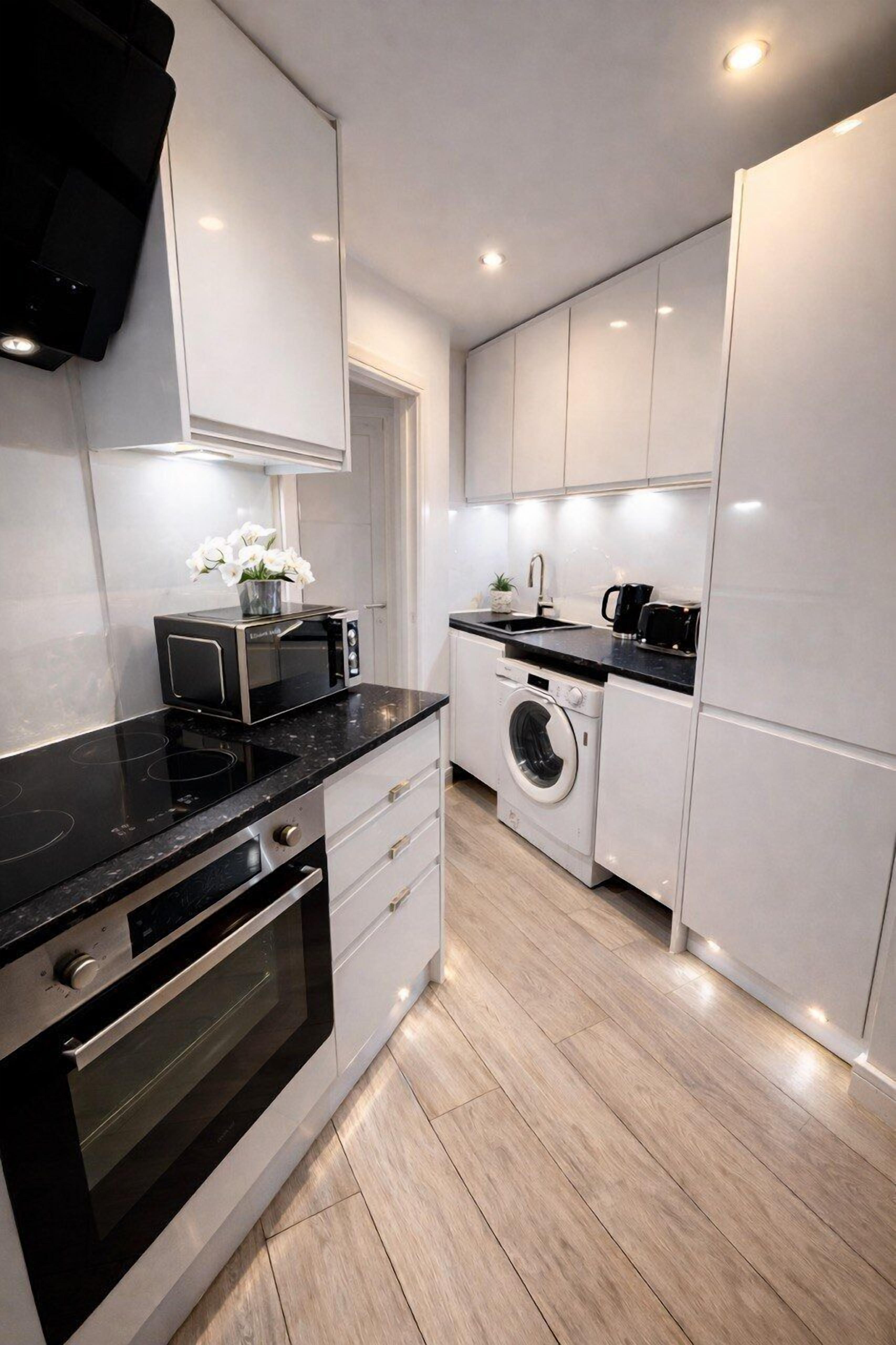 A modern kitchen with a built-in oven, microwave, and washing machine.