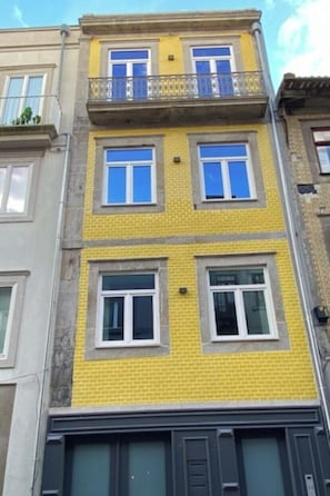 A multi-story building with a yellow facade, balconies, and windows. - Porto Suites (Porto)