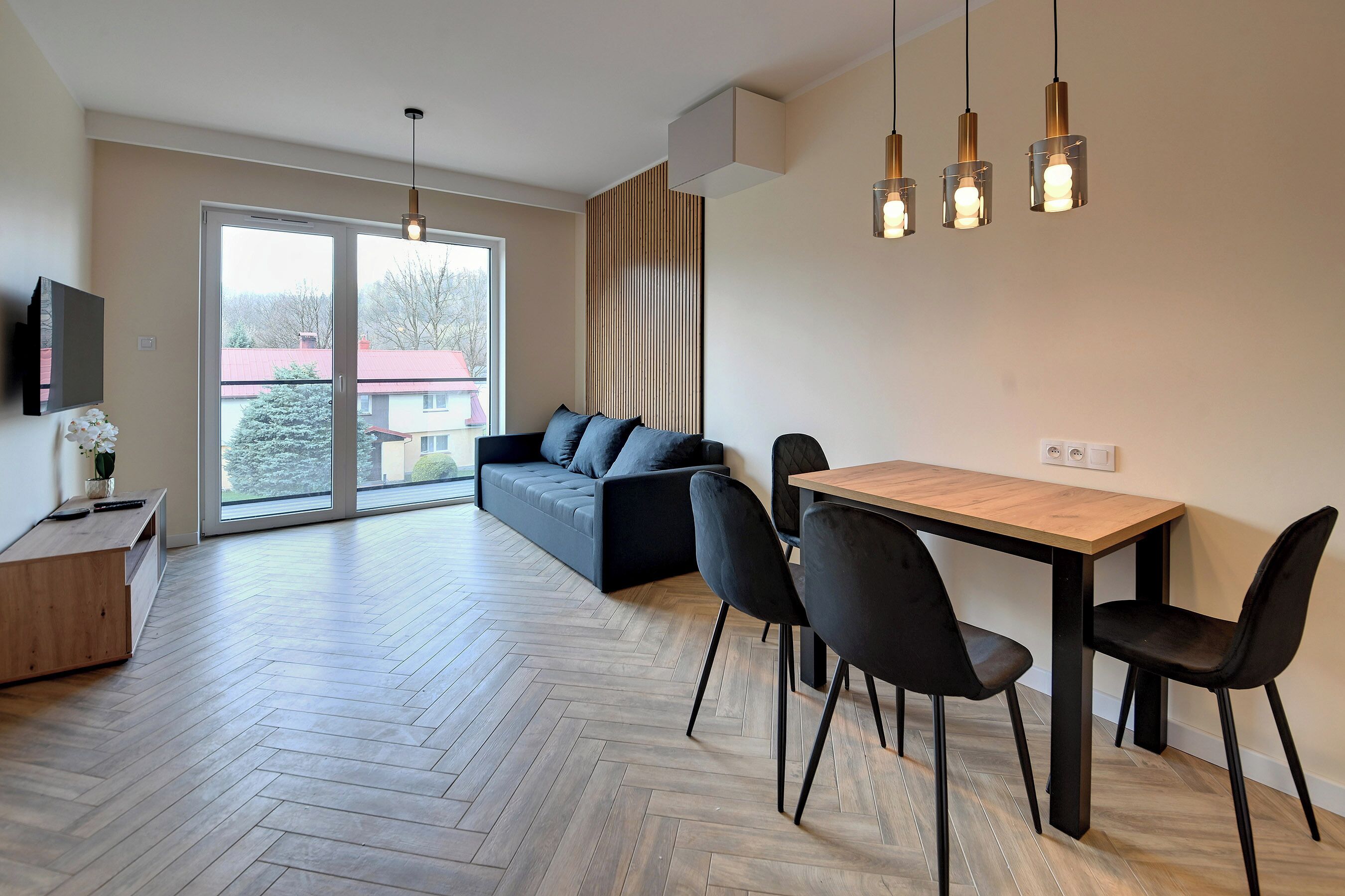 A modern living room with a sofa, dining table, chairs, and a TV.