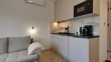 A compact kitchenette with a microwave, coffee maker, and a small sink.