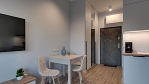 Eine moderne, kompakte Küche mit Essbereich, einem eingebauten Kühlschrank und einem an der Wand befestigten Flachbildfernseher.