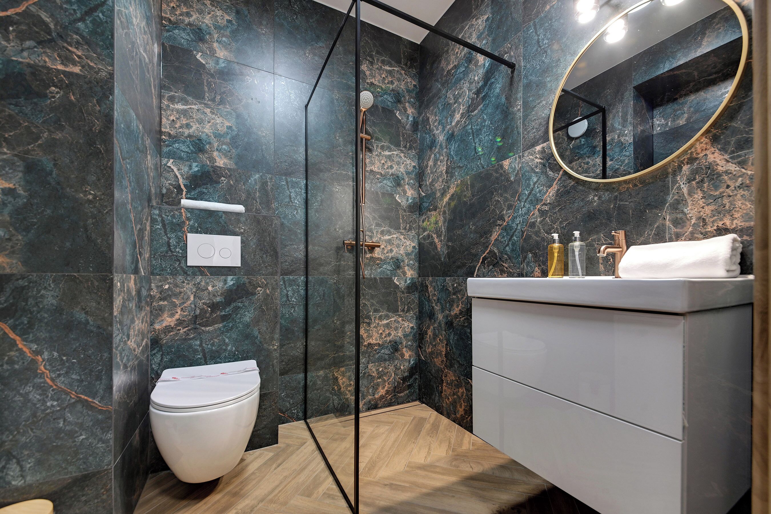 Une salle de bain moderne équipée d’une douche, de toilettes, d’un meuble-lavabo et d’un miroir.