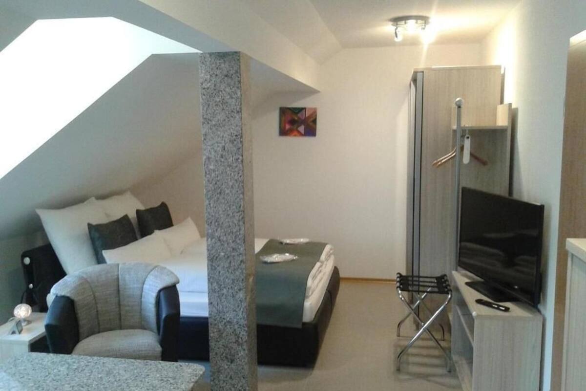 Une chambre d’hôtel moderne équipée d’un lit, d’un bureau, d’une chaise, d’une télévision et d’un espace douche.