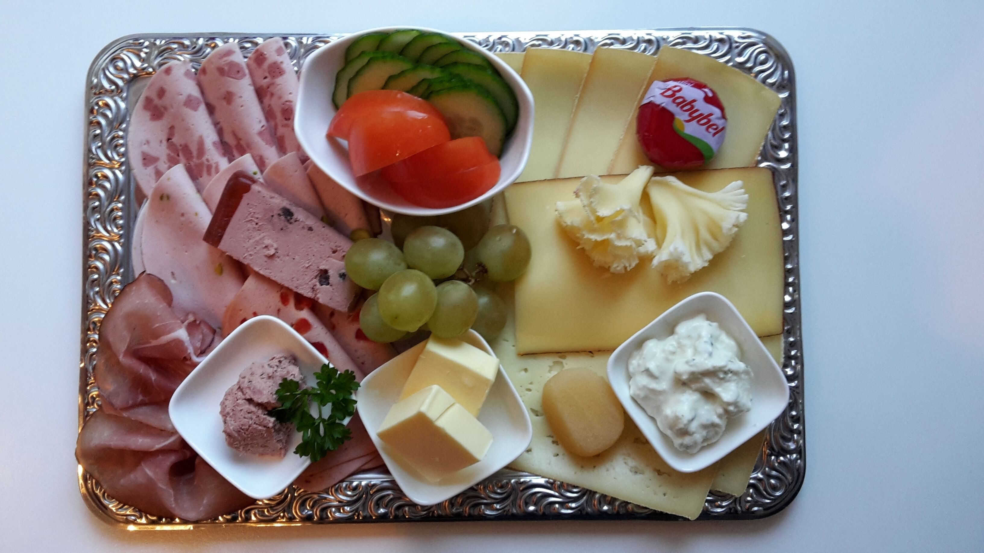 A charcuterie board with various meats, cheeses, fruits, and dips.