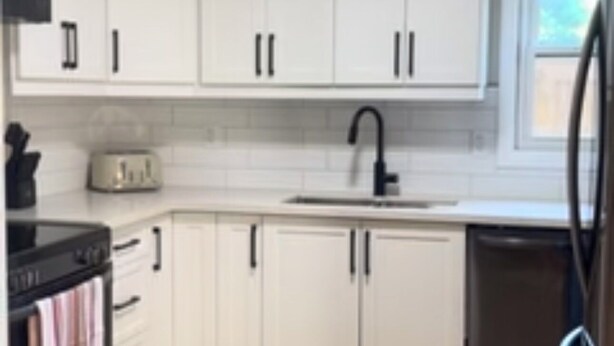 A modern kitchen with white cabinets, a black stove, a toaster, and a dishwasher. - 1 Bed, 1 Bath Private Bungalow in downtown Thorold (Thorold)