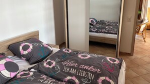A bedroom with a bed, a wardrobe, and a chair. - Cozy vacation apartment on a resettlement farm (Bad Wildungen)