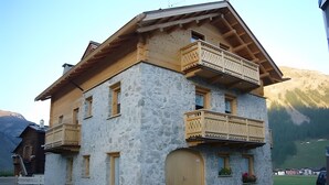 A two-story stone building with wooden balconies and a wooden door. - Apartment '1' with Mountain View, Shared Garden and Wi-Fi (Livigno)