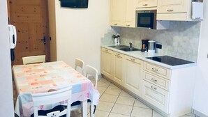 A small kitchen with a table and chairs, a microwave, a stove, and a sink. - Apartment '1' with Mountain View, Shared Garden and Wi-Fi (Livigno)