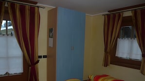 Un dormitorio con cama, armario y cortinas.