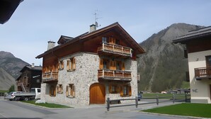 Un edificio de piedra de dos pisos con balcones de madera y una puerta de madera.