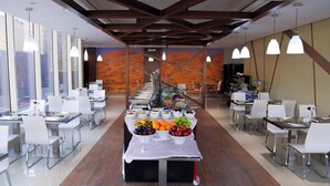 Un comedor moderno con una mesa larga mostrando diversas frutas y un sistema de bufé.
