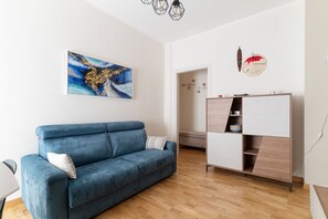 Ein modernes Wohnzimmer mit einem blauen Sofa, einem Holzschrank und einem Gemälde an der Wand.