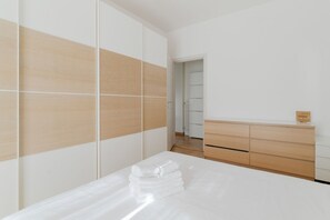 Ein modernes Schlafzimmer mit einem Bett, einem Holzschrank und einer Kommode.