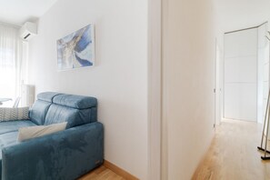 Ein modernes Wohnzimmer mit einem blauen Sofa, einem Gemälde an der Wand und Holzboden.