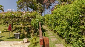 A garden with a stone pathway leading to a wooden bench, a small pool, and a pergola with climbing plants. - Casa em Igaratá com Piscina Lareira e Vista Lago (Igaratá)