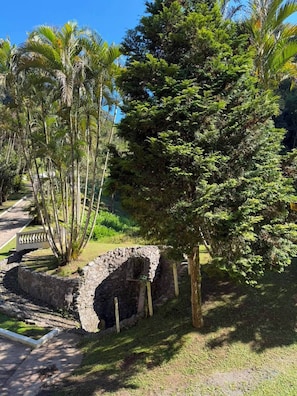 Una estructura de piedra con un sendero que la conduce, rodeada de vegetación exuberante y árboles.