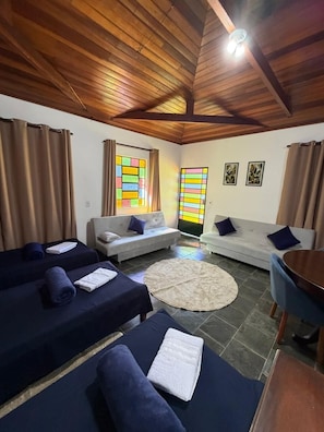 A room with two beds, a sofa, a round rug, and a dining table. - VERDE VALLE POUSADA (Sao Lourenco da Serra)