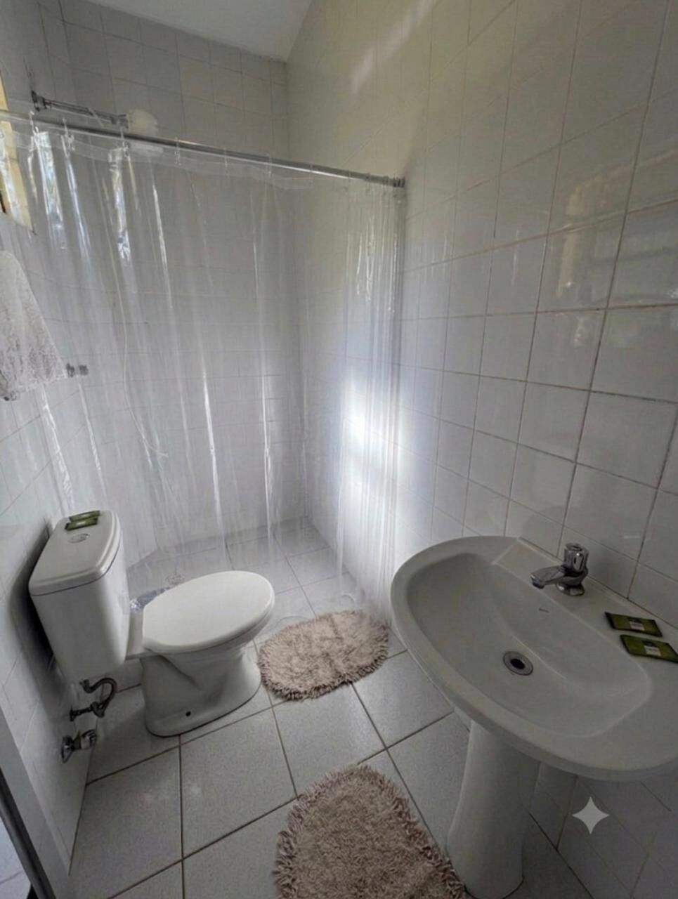 Un baño con inodoro, lavamanos y cortina de ducha.