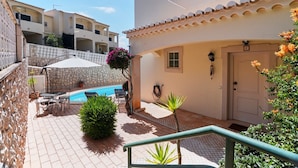 Ein Innenhof mit Swimmingpool, Terrassenmöbeln und einer mit 'F' gekennzeichneten Tür.