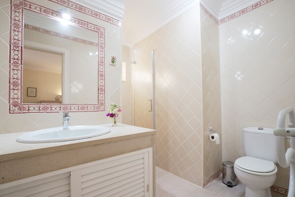 A bathroom with a white sink, mirror, and toilet.