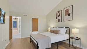 Un dormitorio con una cama, mesitas de noche y obras de arte en las paredes.
