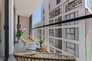 Un balcon avec des fauteuils en osier, une petite table ronde et une plante en pot.