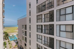 Un immeuble à plusieurs étages doté de balcons, d’une piscine et offrant une vue sur l’océan.