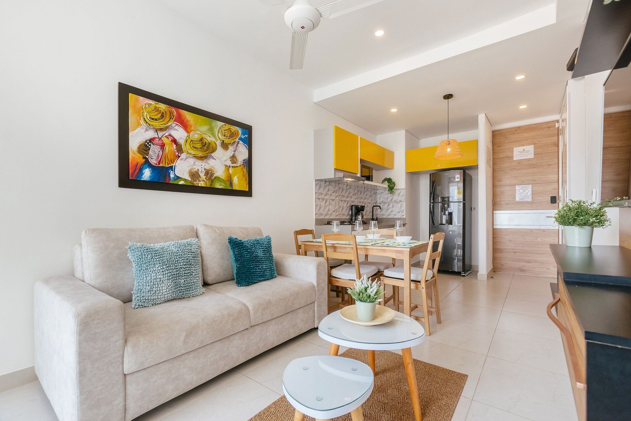Una sala de estar moderna con sofá, una mesa de comedor y una cocina al fondo.