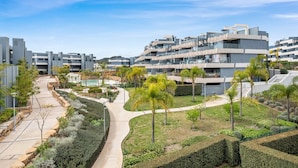 Un complejo residencial moderno con varias construcciones, un camino central y zonas ajardinadas con árboles y arbustos.