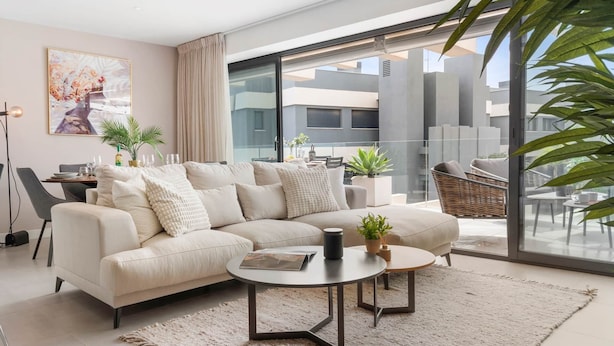 Una sala de estar moderna con sofá, mesa de centro y plantas en macetas.