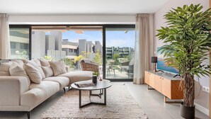 Una sala de estar moderna con un sofá, una mesa de centro y un ventanal con vistas a la ciudad.