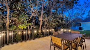An outdoor patio with a table and chairs, surrounded by a fence with string lights. - 🏖️2 Community Pools | Close to Beach | Barefoot Villa☀️ (Panama City Beach)