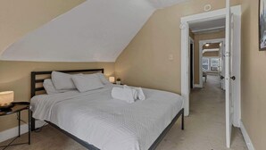 Una camera da letto con un letto, una lampada da comodino e una porta che dà su un'altra stanza.