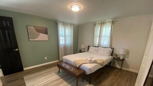 Una camera da letto con un letto, una panca, un comodino e un’opera d’arte appesa al muro.